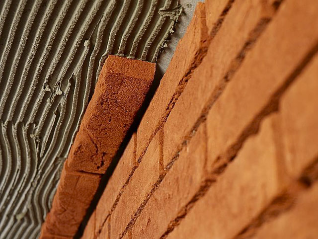Close-up van mortel die tegen een gevel wordt aangebracht.